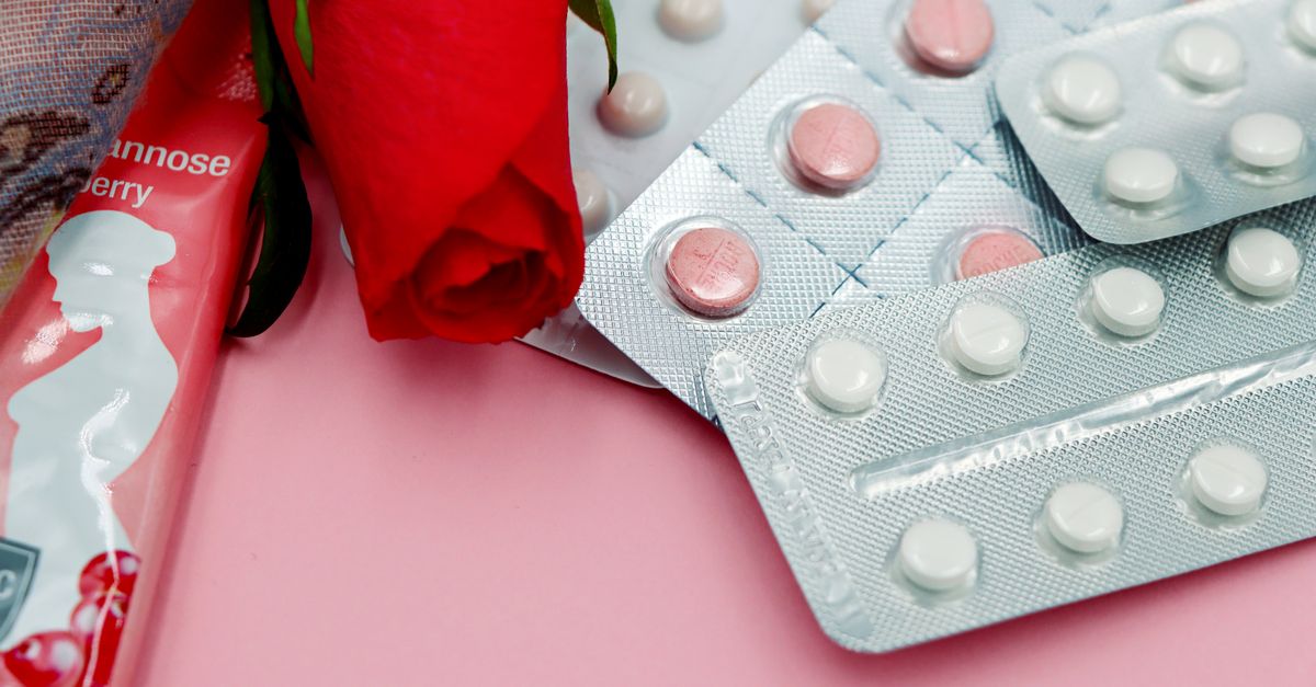 Pills and red rose on pink background, symbolizing healthcare and romance.
