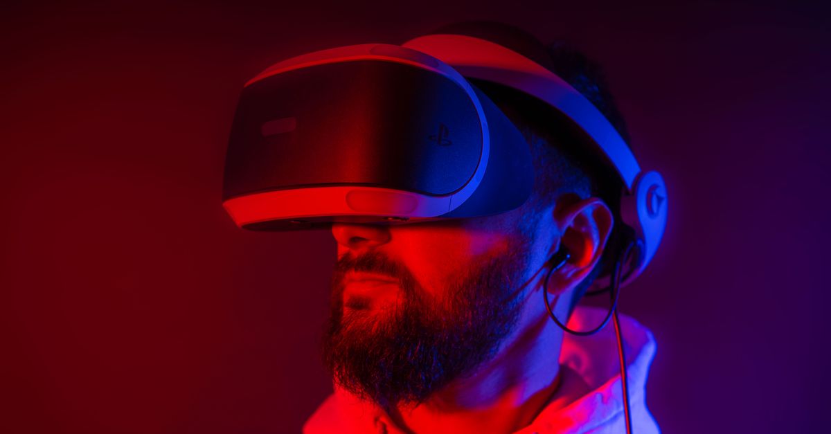 Young bearded man entertaining with VR glasses in colorful neon light on black background
