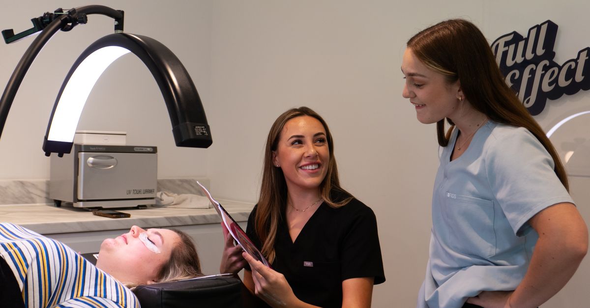 Two dermatologists consult with a patient in a modern clinic setting.