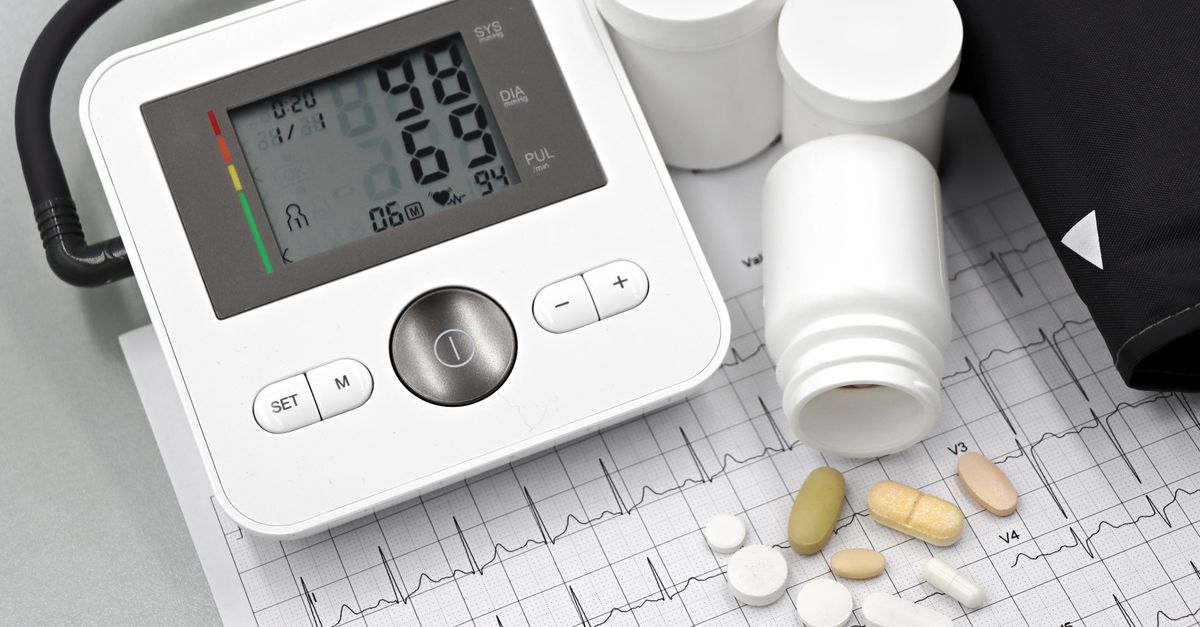 Blood pressure monitor with pills on ECG sheet, essential for heart health management.