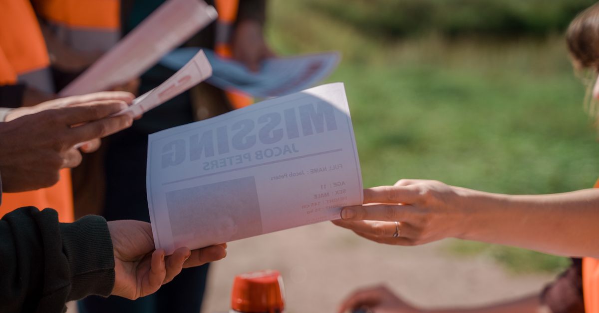 Group of volunteers handing out missing person flyers during a search operation outdoors.