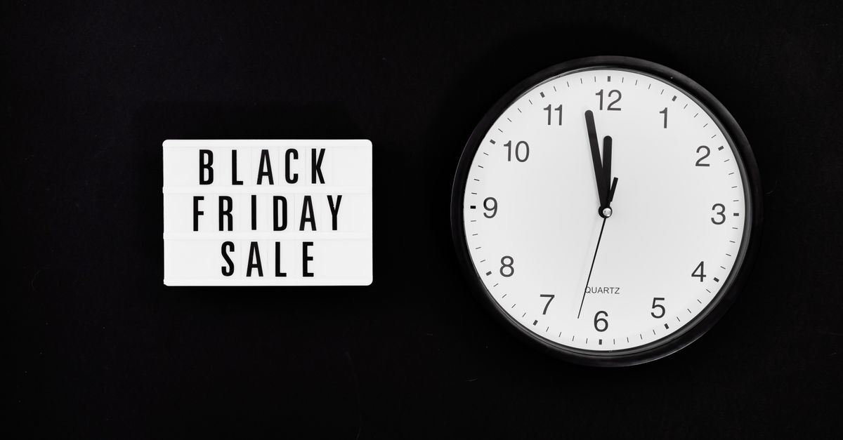 Minimalist clock with a Black Friday sale sign on black background, highlighting a midnight sale countdown.