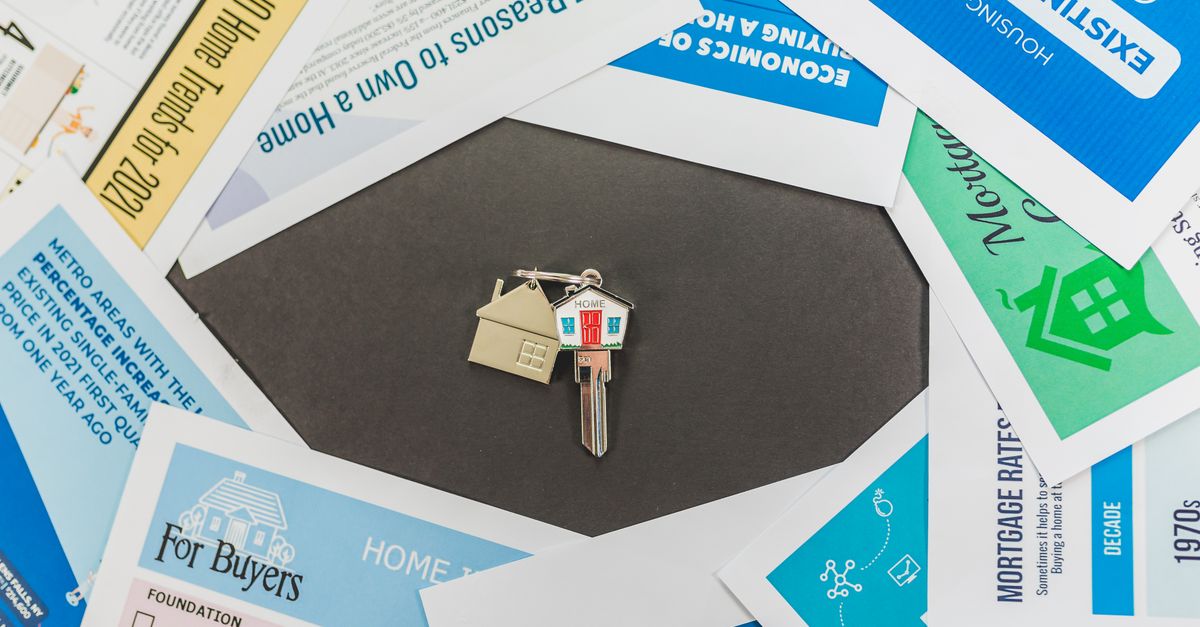 Overhead view of real estate brochures and house key, ideal for marketing.