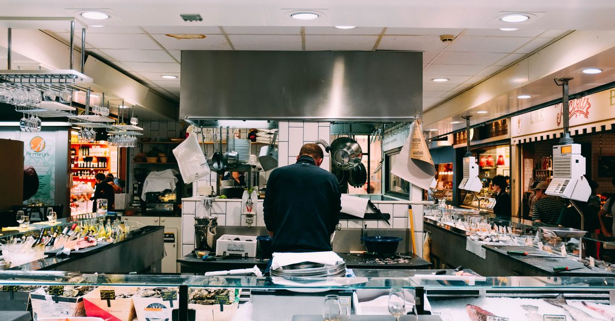 Chef preparing fresh seafood in a bustling indoor market setting.