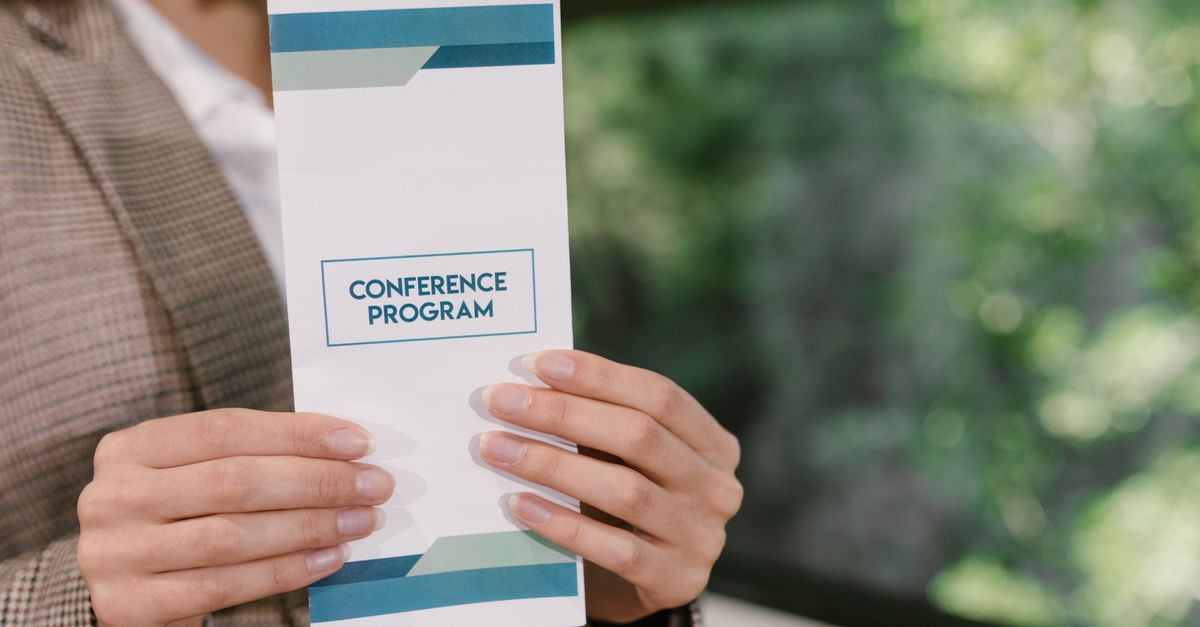 A professional holding a conference program brochure, ready for event attendees.