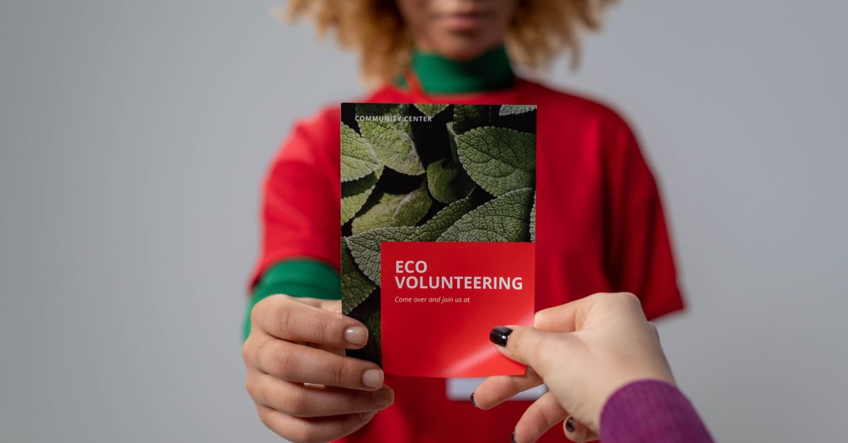 Close-up of hands exchanging an eco volunteering brochure, representing environmental awareness.