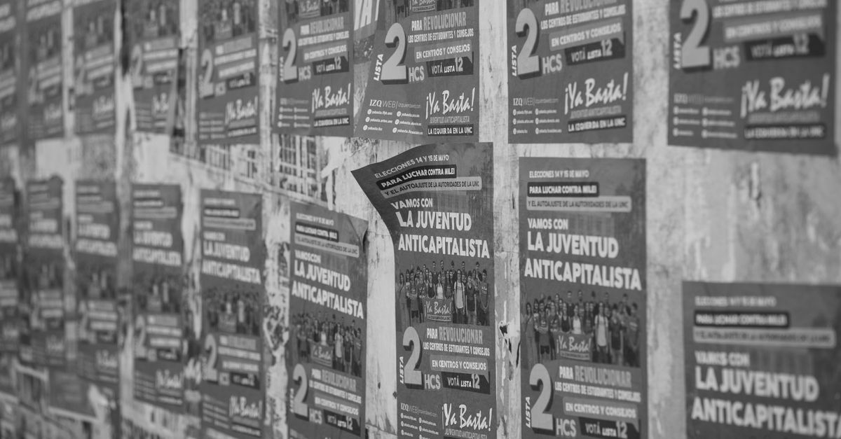 Street covered with political posters promoting anti-capitalist youth movements in Cordoba.