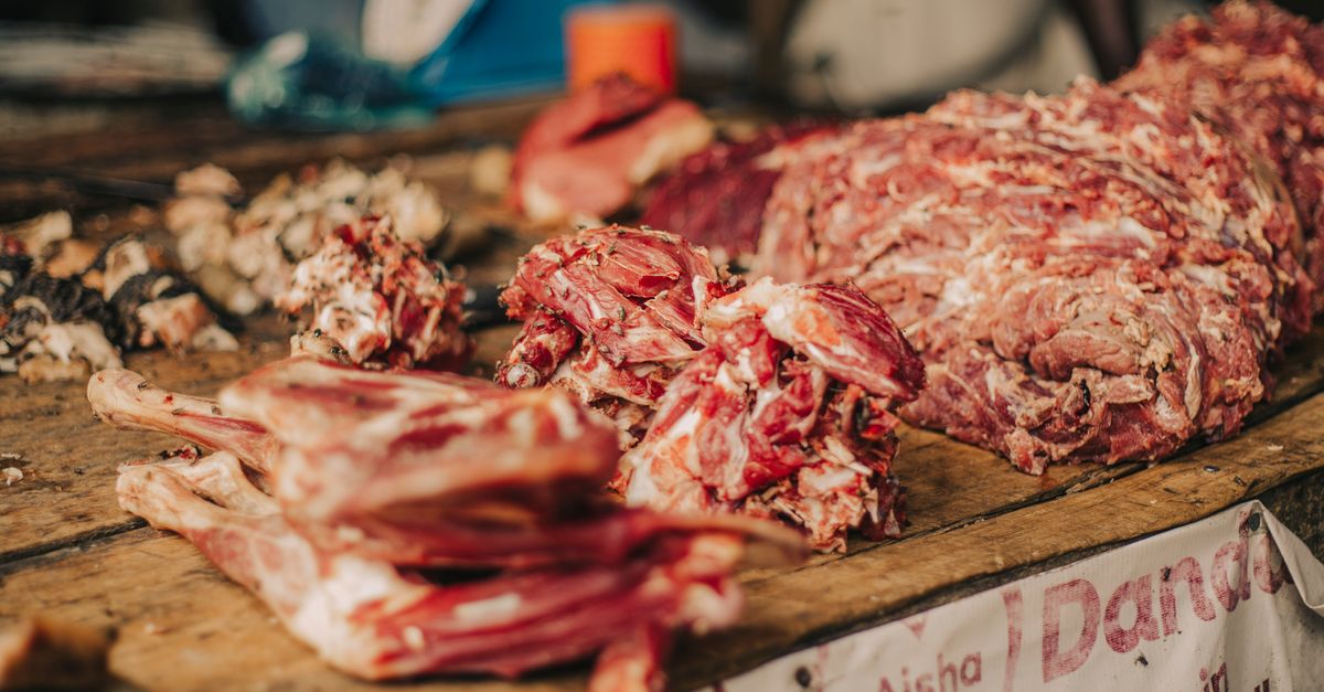 Close-up of fresh meat cuts displayed on a wooden market table, perfect for culinary visuals.