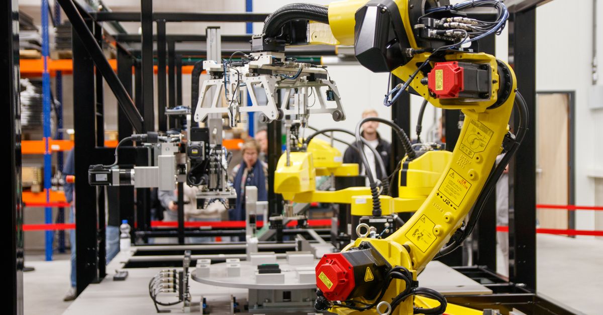 Close-up of a yellow industrial robotic arm in action at a modern manufacturing facility.