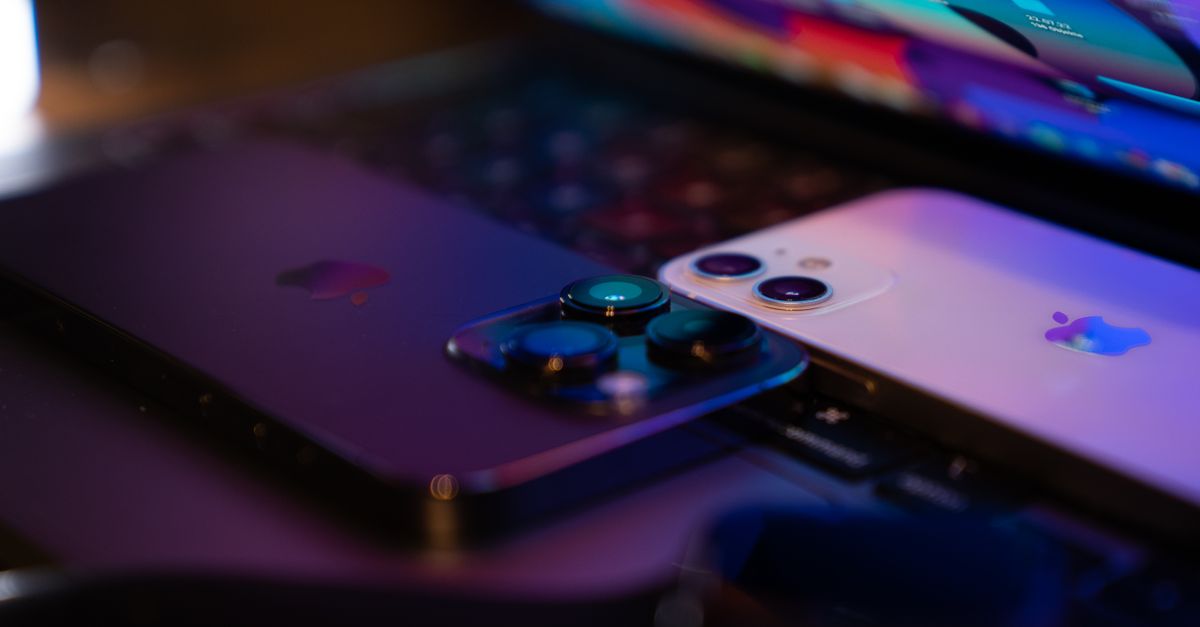 Close-up image of two modern smartphones placed on a laptop keyboard, highlighting technology design.