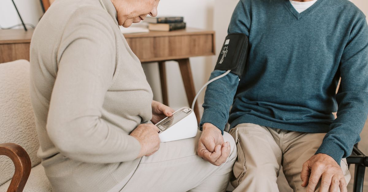 Senior couple at home measuring blood pressure for health check.