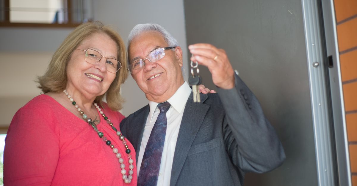 Elderly couple happily holding keys, symbolizing new homeownership.