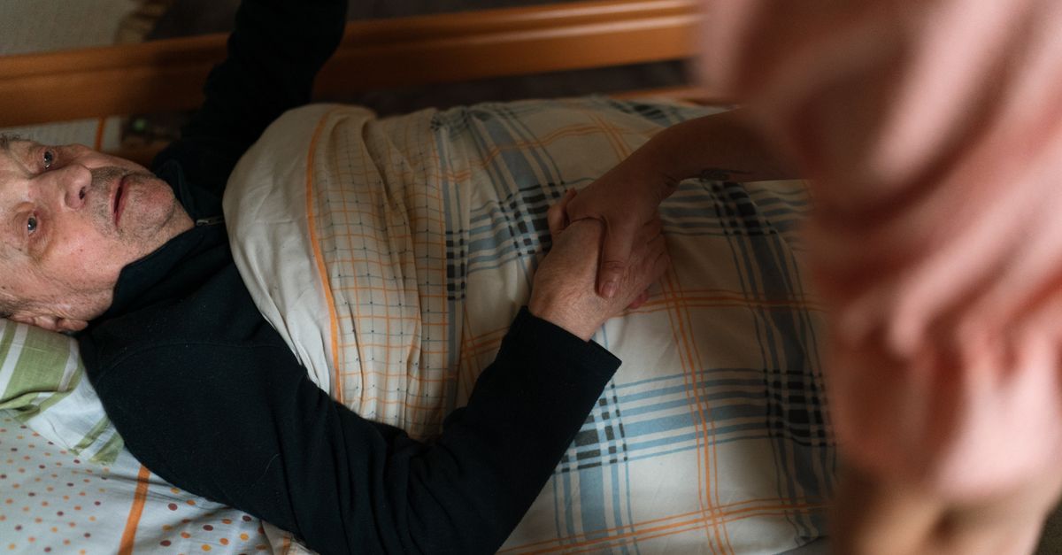 A caregiver holding hands with a senior adult, providing support and reassurance at home.