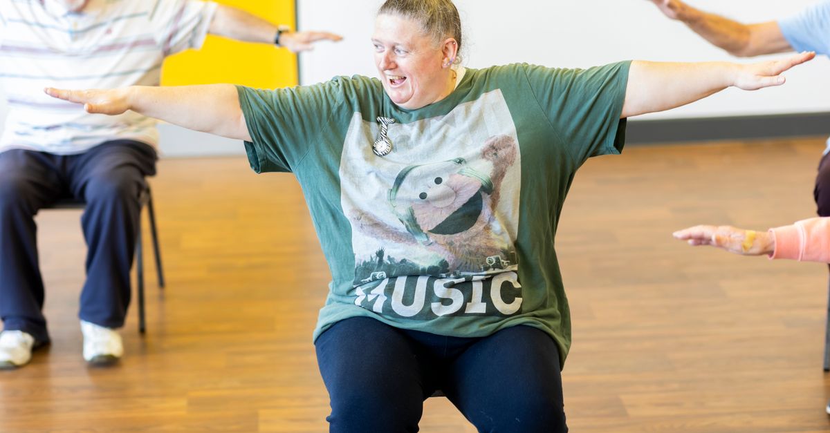 Seniors participating in a seated exercise class, promoting community health and active aging.