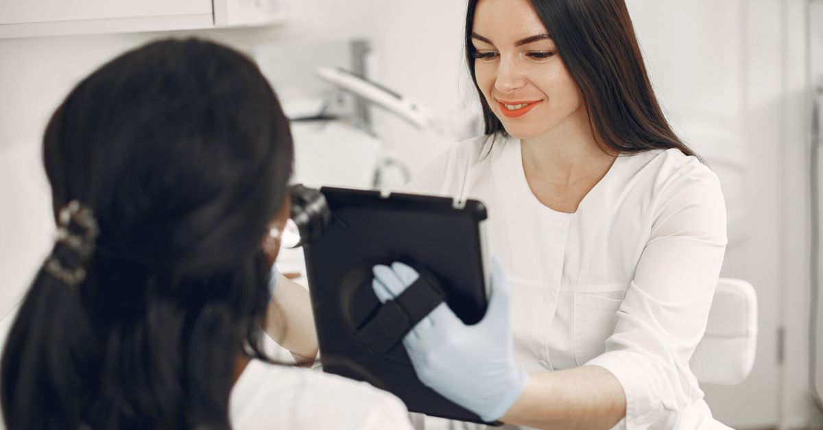 A beautician consults a client using a tablet in a modern beauty spa setting.