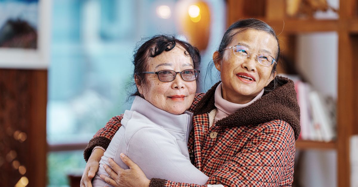 Two senior women embracing, expressing warmth and friendship indoors.