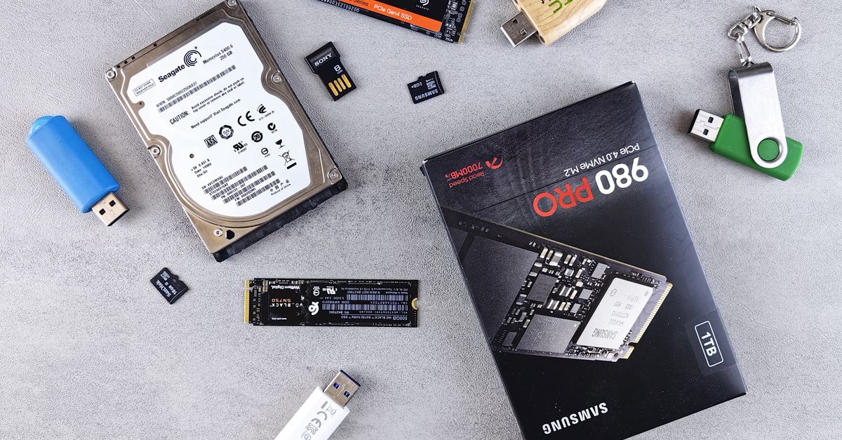 Flat lay of various computer data storage devices on a gray surface.