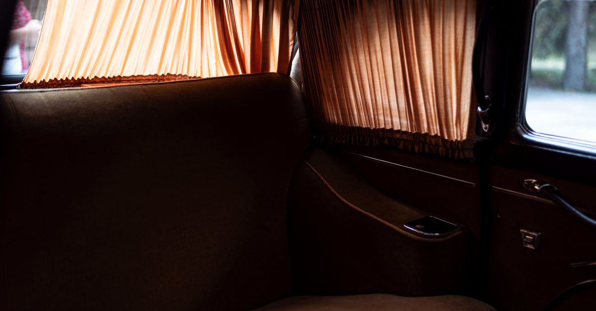 Explore the luxurious interior of a vintage car featuring classic curtain design and rich upholstery.