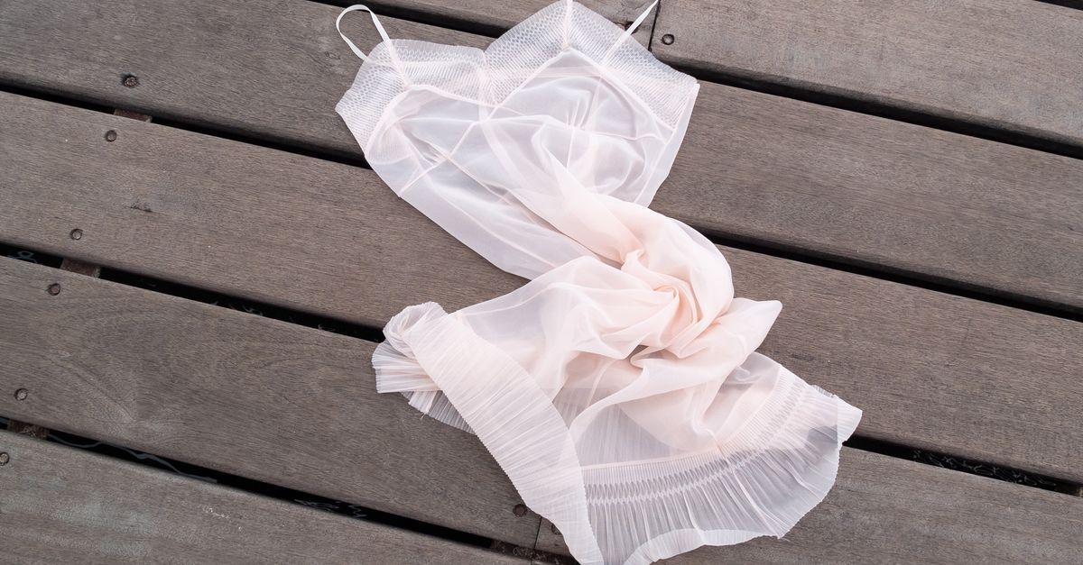 Elegant sheer pink lingerie elegantly draped on a wooden surface, ideal for fashion and lifestyle contexts.