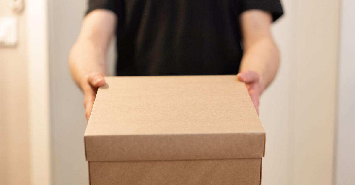 Close-up of a person holding a cardboard box, ideal for delivery service concepts.