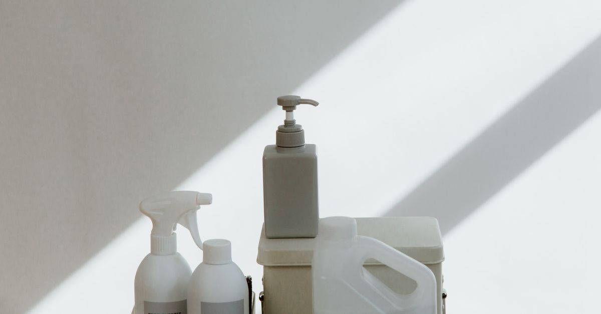 A collection of cleaning products on a minimalist background with dramatic shadows.