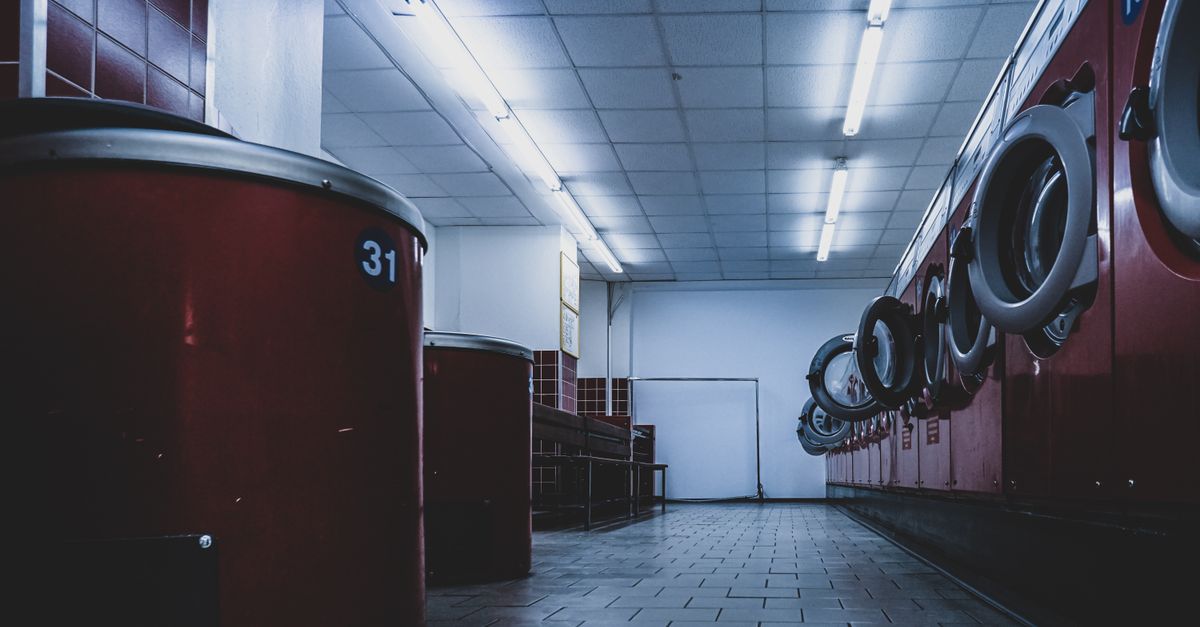 Interior view of a contemporary laundromat featuring red washing machines under fluorescent lights.
