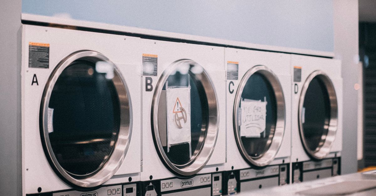 A series of industrial washing machines labeled A to D in a modern laundromat setting.
