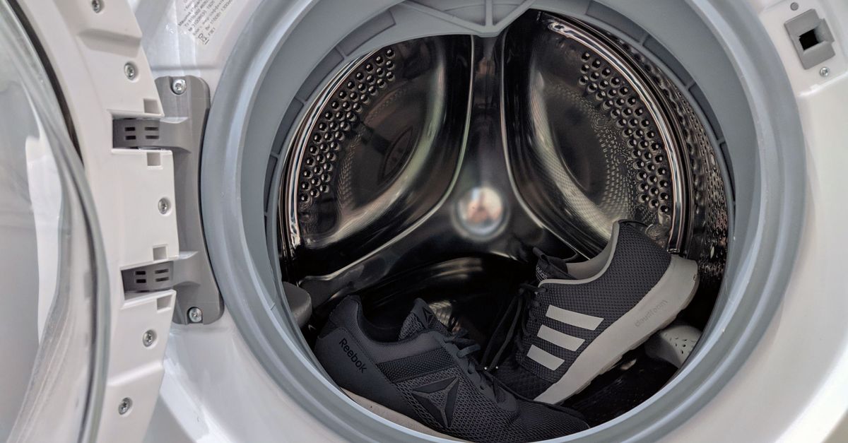 Close-up of black sneakers inside a washing machine drum showcasing laundry theme.