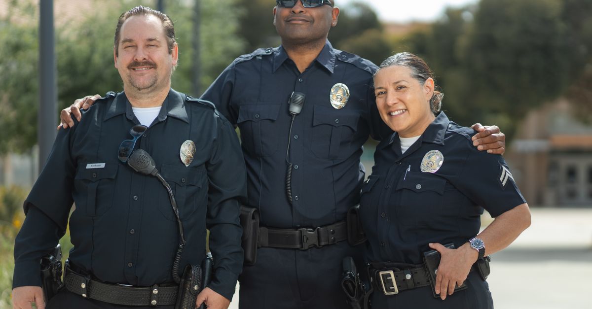 Diverse group of police officers in uniform smiling together outdoors.