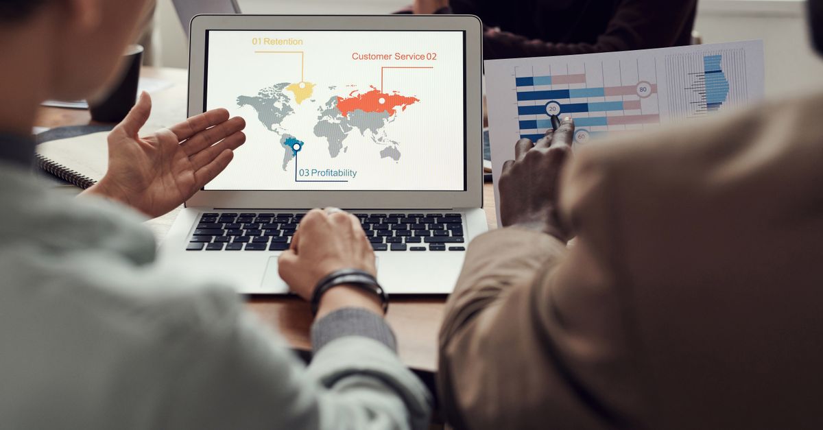 Team collaborating on business strategy with laptop displaying global analytics.