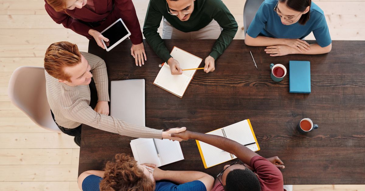 Top view of a diverse business team meeting with a handshake across the table. Collaborative working environment.