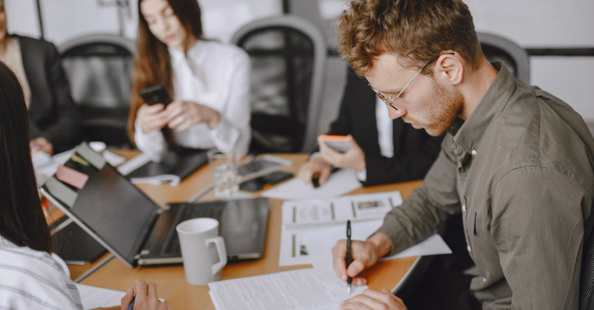Business professionals engaged in a corporate meeting, emphasizing document signing and collaboration.
