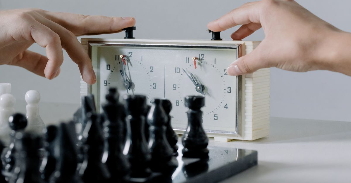 Close-up of hands pressing chess clock during an intense board game session.