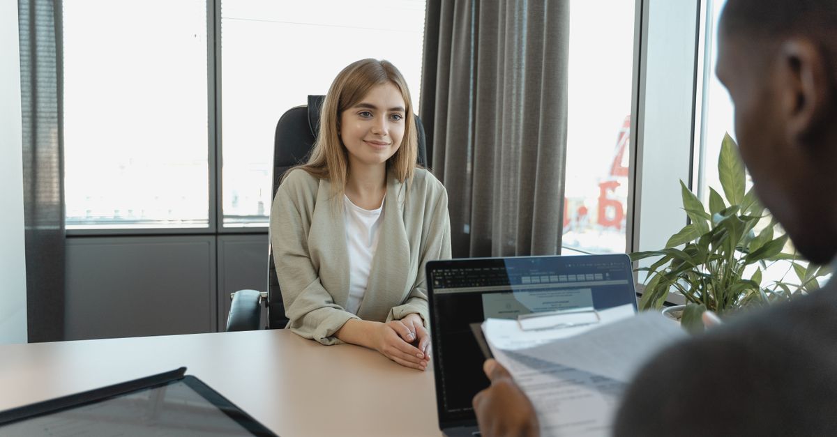 Young woman sitting confidently in a modern office for a job interview.