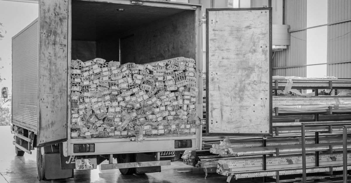 Black and white image of an open delivery truck in an indoor warehouse setting.