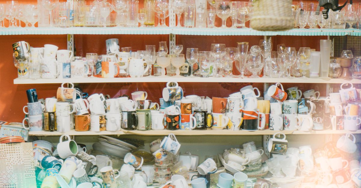 Assorted glassware and ceramic mugs organized on store shelves, showcasing variety and abundance.