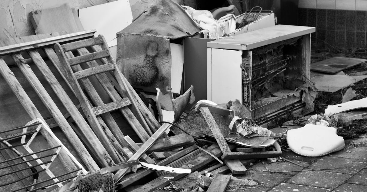Black and white image of a pile of discarded objects in an urban setting, highlighting decay.