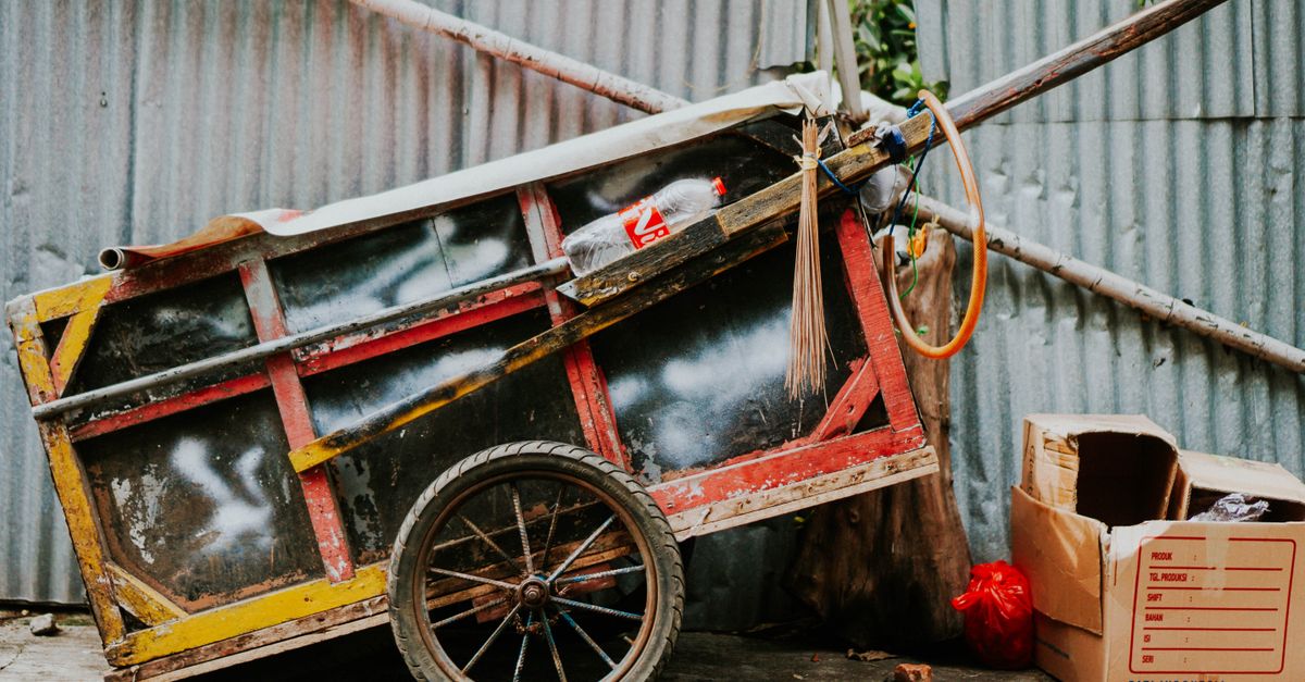 A colorful, rustic cart leans against a corrugated metal wall in Jakarta.