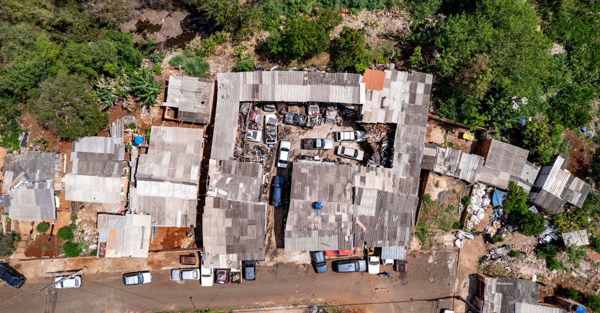 Aerial view of a cluttered junkyard surrounded by lush greenery in Londrina, Brazil.