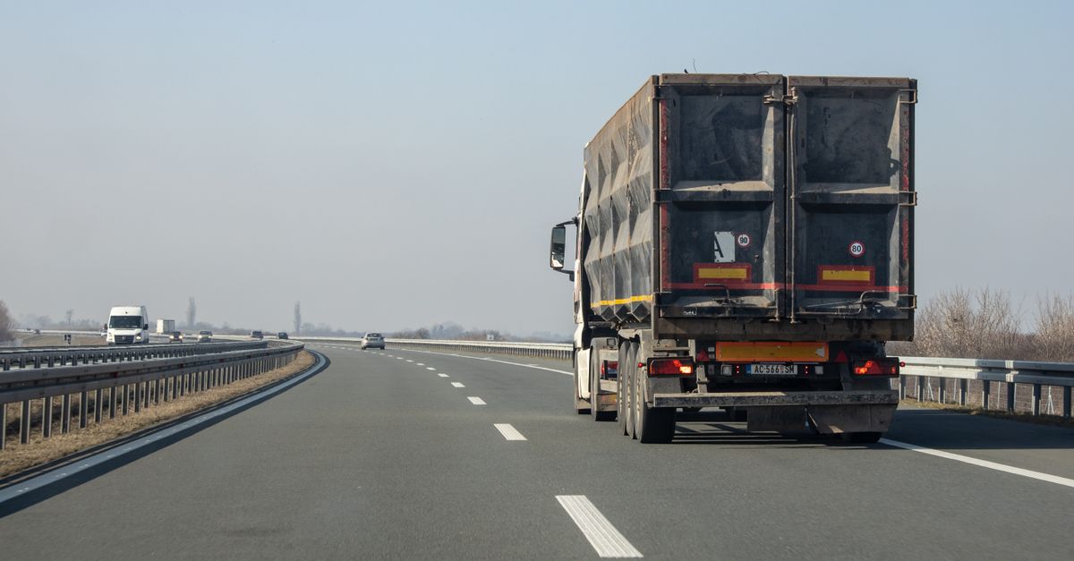 A cargo truck travels down an empty highway on a clear day, showcasing transportation and logistics.