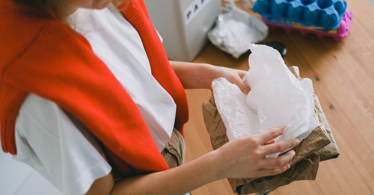 Crop anonymous female in casual clothes sorting out rubbish while standing in light apartment in daytime