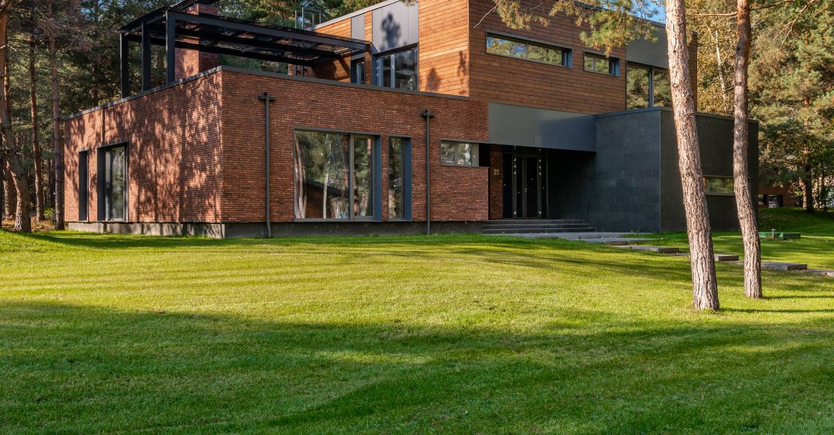 Contemporary house with large windows surrounded by lush greenery and trees.