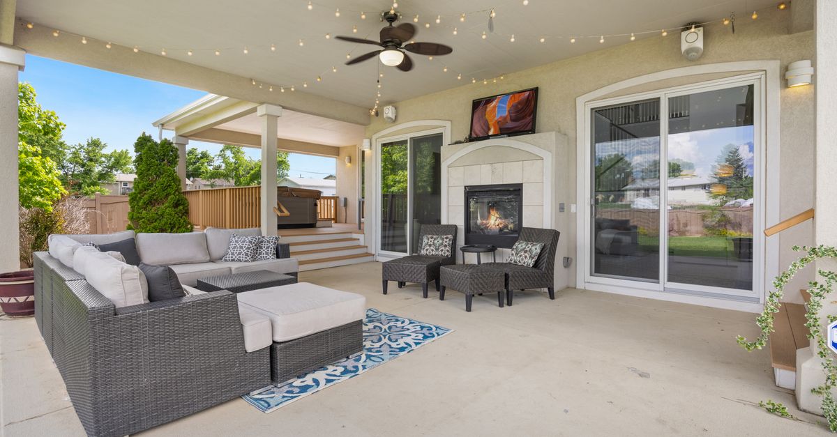 Luxurious outdoor patio featuring a cozy fireplace, modern furniture, and ambient string lights for a perfect relaxation spot.