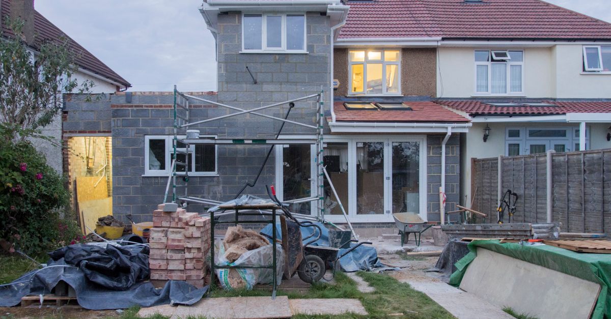 A suburban house undergoing major renovations with scaffolding and building materials.