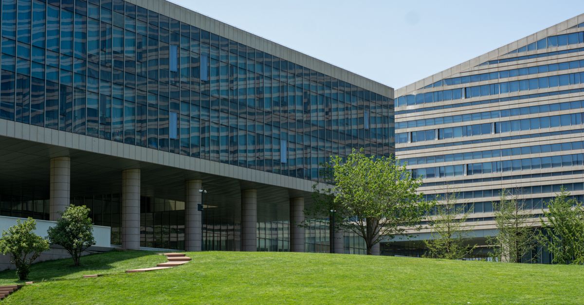 Contemporary glass office building surrounded by lush green grass in daylight.