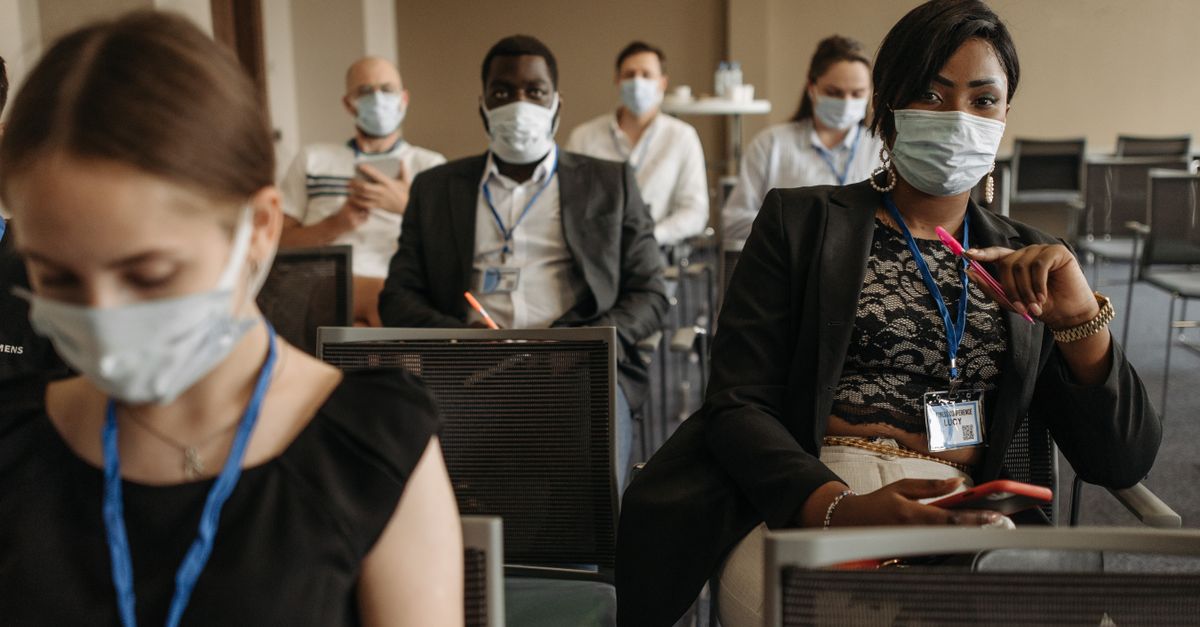 Business conference attendees wearing masks highlighting new normal and diversity in modern meetings.