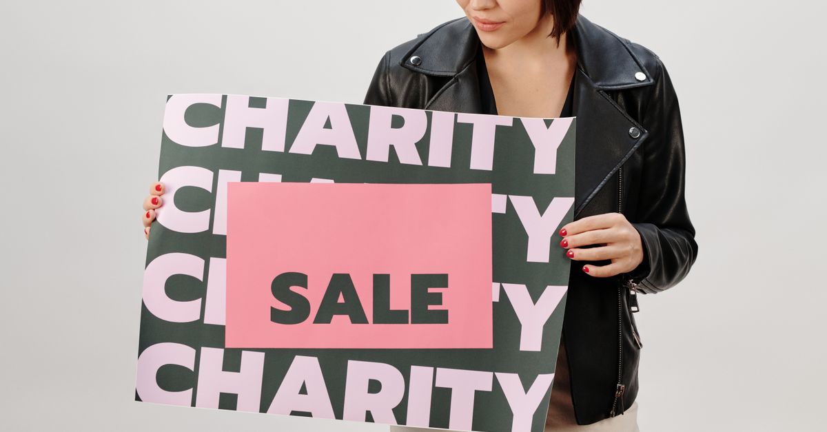 Woman holding a charity sale sign in a studio setting.