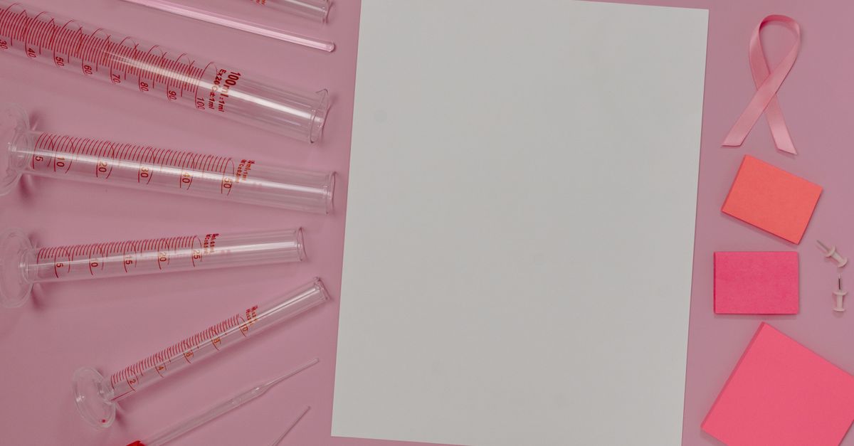 Flat lay of pink laboratory and office supplies promoting breast cancer awareness.