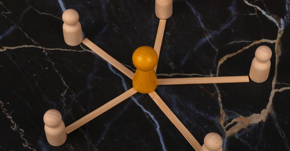 Wooden figures arranged in network pattern on dark marble background, symbolizing communication.