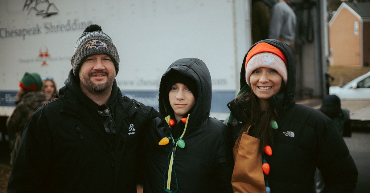 Group of volunteers enjoying a winter holiday event outdoors, dressed in festive attire.
